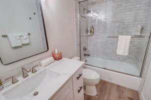Located between the guest bedrooms, this shared separate full bathroom is complete with large vanity and shower-tub combo