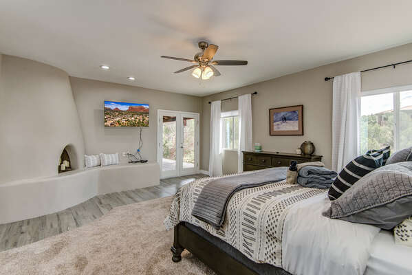 Grand Master Bedroom with a King Bed, Smart TV, a decorative fireplace (not operational),  and Patio Access