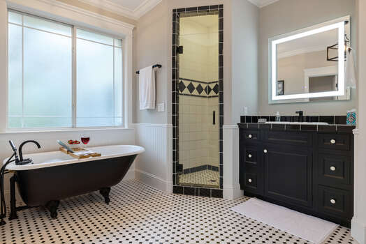 En suite master bath with a shower, soaking tub, and two separate vanities with lighted mirrors