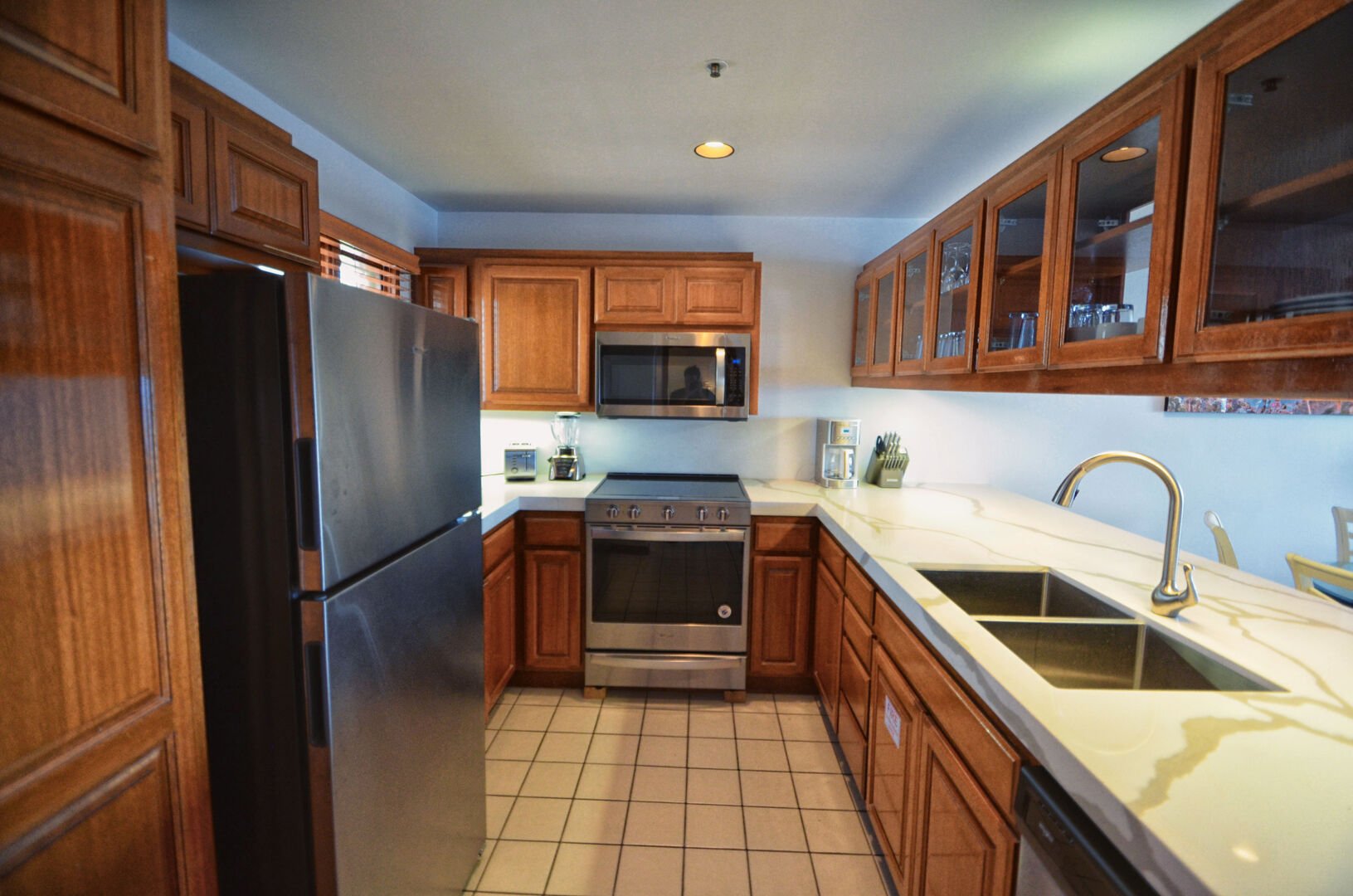 Kitchen with quartz countertops, stainless steel appliances, coffee maker, blender, sink, toaster
