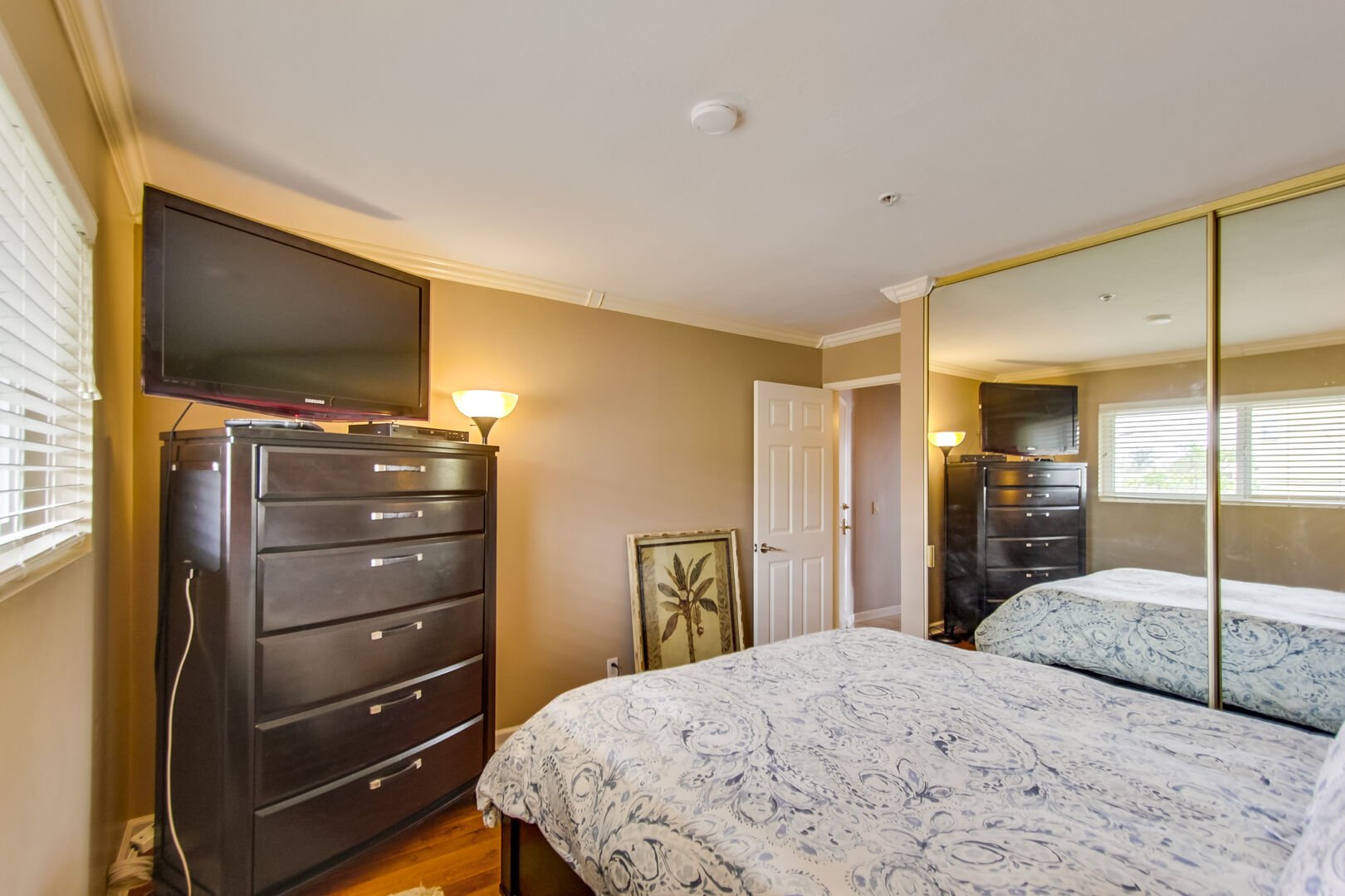 Bedroom with queen bed, TV, mirrored closets and lamps