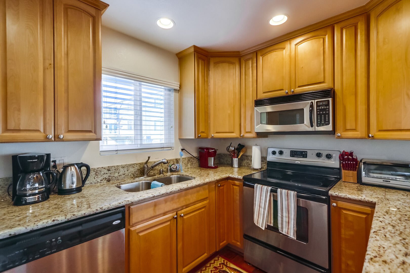 Kitchen with stainless steel appliances, granite countertops, sink, dishwasher, refrigerator, coffee maker, toaster, and blender