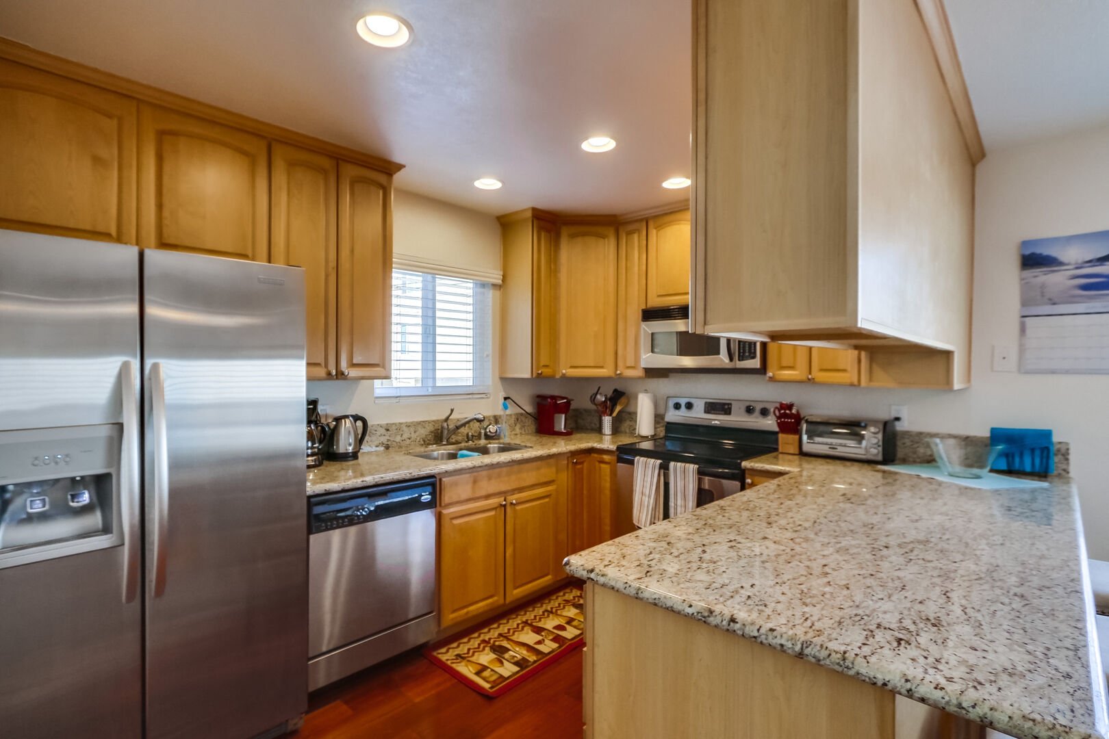 Kitchen with stainless steel appliances, granite countertops, sink, dishwasher, refrigerator, coffee maker, toaster, and blender