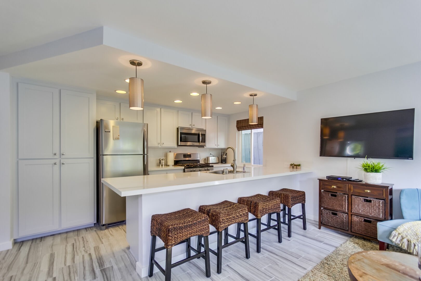 Open California-style kitchen with recessed lighting, bar seating for 4, and stainless steel appliances