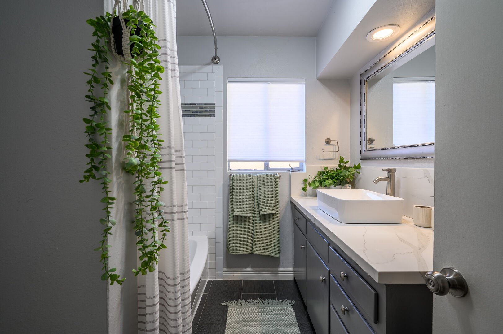 Shared hallway guest bathroom with shower-tub combo with large vanity