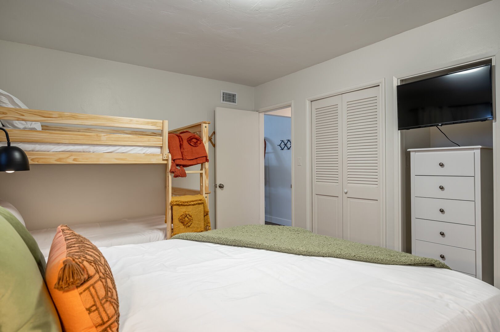 Guest bunk bedroom with twin bunk beds and separate queen bed, TV and dresser storage
