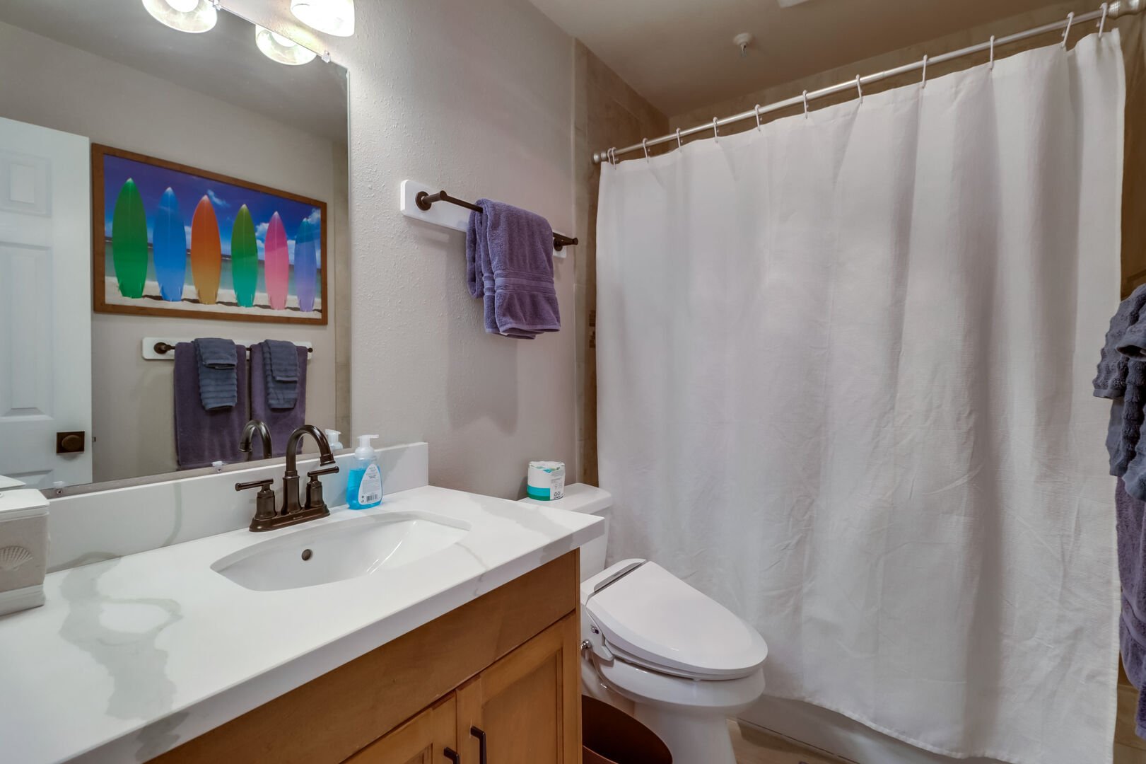 Shared bathroom with large vanity, recessed lighting and shower-tub combo