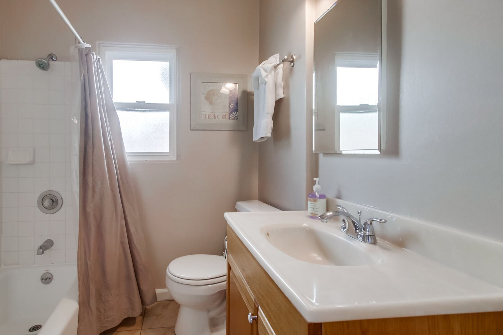 Shared bathroom with vanity, toilet, mirror, overhead lighting, and shower-tub combination