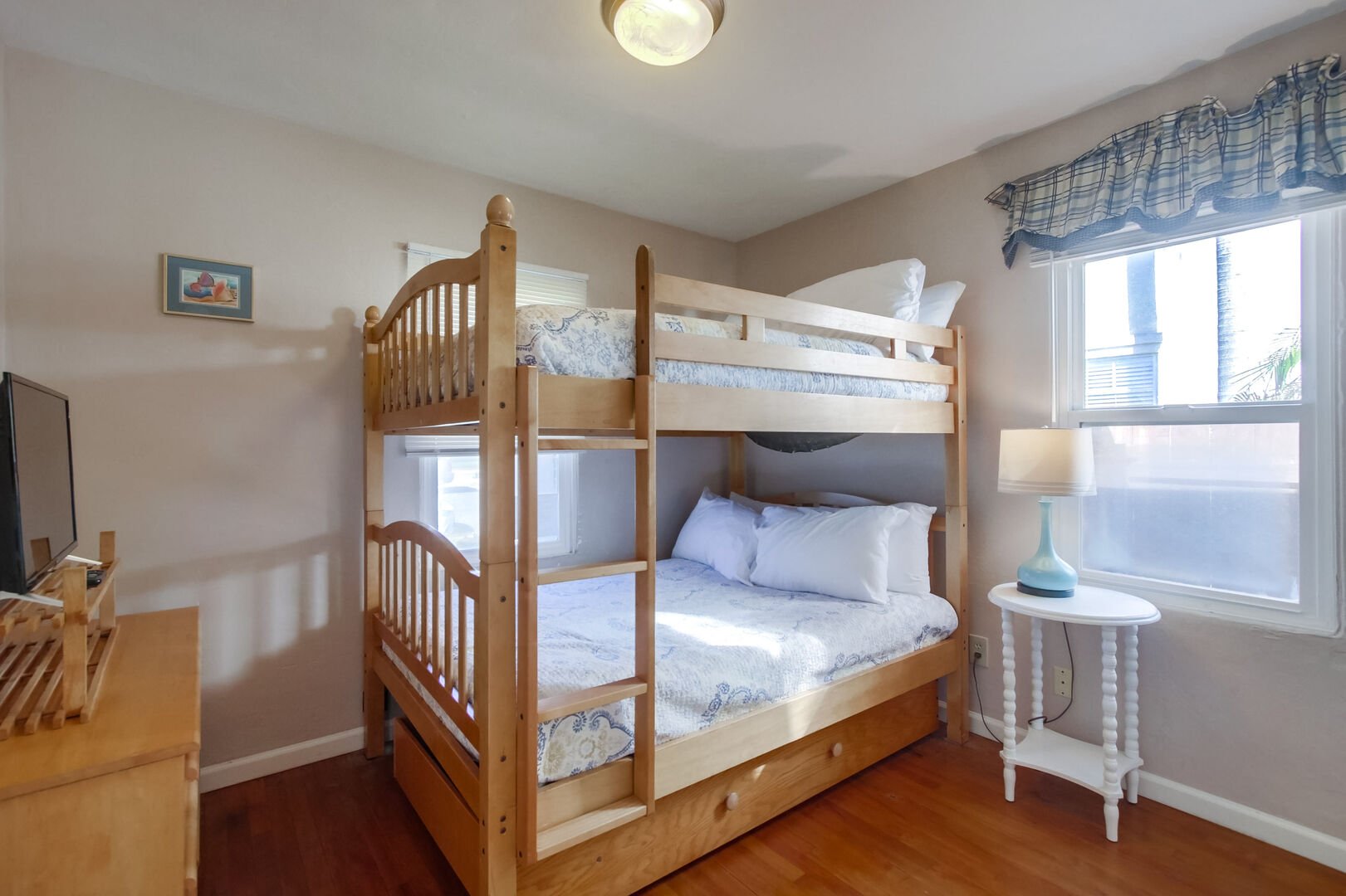 Guest bedroom with double size bunk beds, lamps, overhead lighting, dresser, and lots of natural light