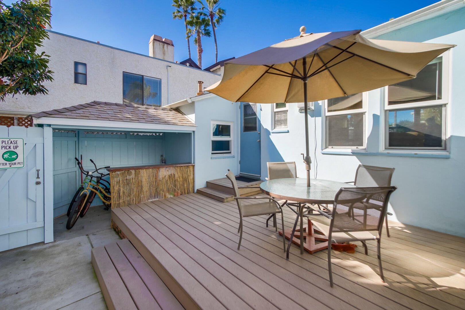 Large patio space with dining, BBQ, beach accessories, artificial grass - fully enclosed yard, great for meals under the stairs, furry friends, and entertaining!