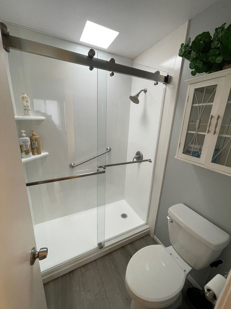 Walk-in shower! Vanity and toilet with overhead sconce lighting