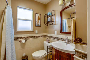 Bathroom with overhead lighting, vanity sink and mirror, toilet, and shower/ tub combination