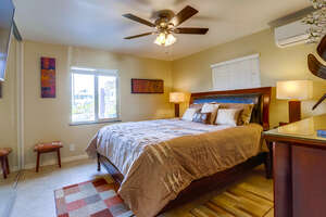 Bedroom with king size bed, ceiling fan, TV, dresser with mirror, AC unit, lamps