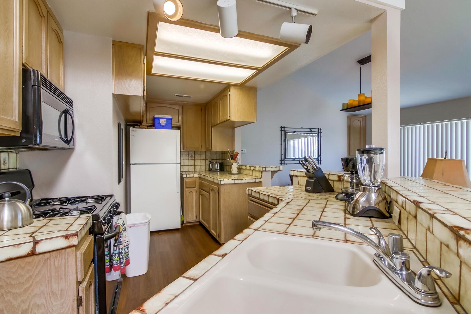 Kitchen with refrigerator, toaster, microwave, overhead lighting, sink, blender