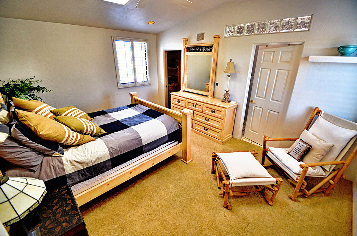 Master bedroom with queen size bed, large closet, comfy chair, sky light, ceiling fan, lamps, and dresser with mirror