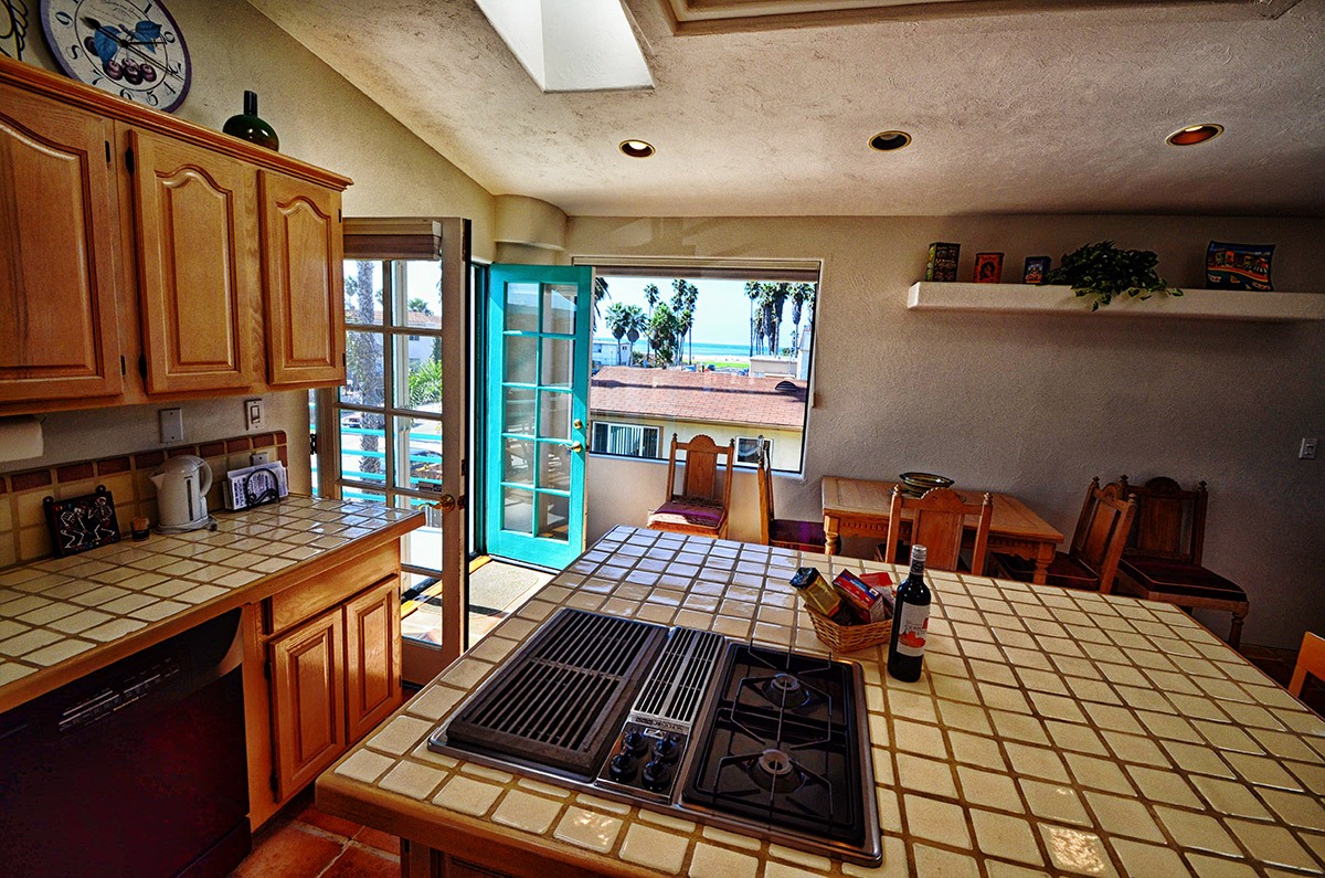 Kitchen with large island in the center,  sliding glass doors to private patio, and seating for 4-6 guests