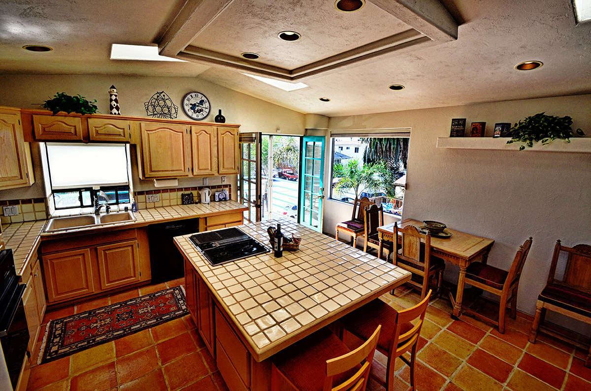Kitchen with large island in the center, refrigerator, microwave, dishwasher, sink, coffee maker, sliding glass doors to private patio, and seating for 4-6 guests