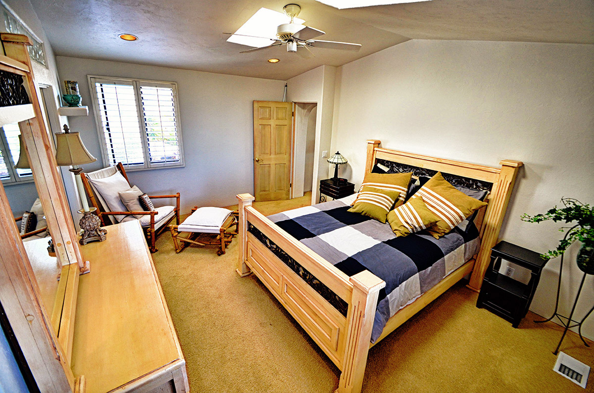 Master bedroom with queen size bed, large closet, sky light, ceiling fan, lamps, and dresser