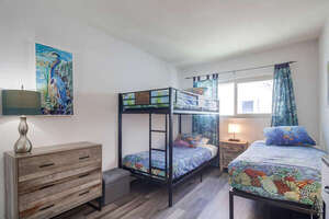 Bedroom with 2 twin bunk beds, an additional twin bed, TV, mirrored closet and dresser