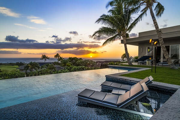 The tropical Hawaiian sun sets over the azure Pacific as family and friends gather on the lanai and Baja deck of the pool