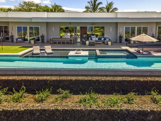 Relax on the expansive lanai after swimming laps in the full-length infinity edge swim pool of this Mauna Kea house rental