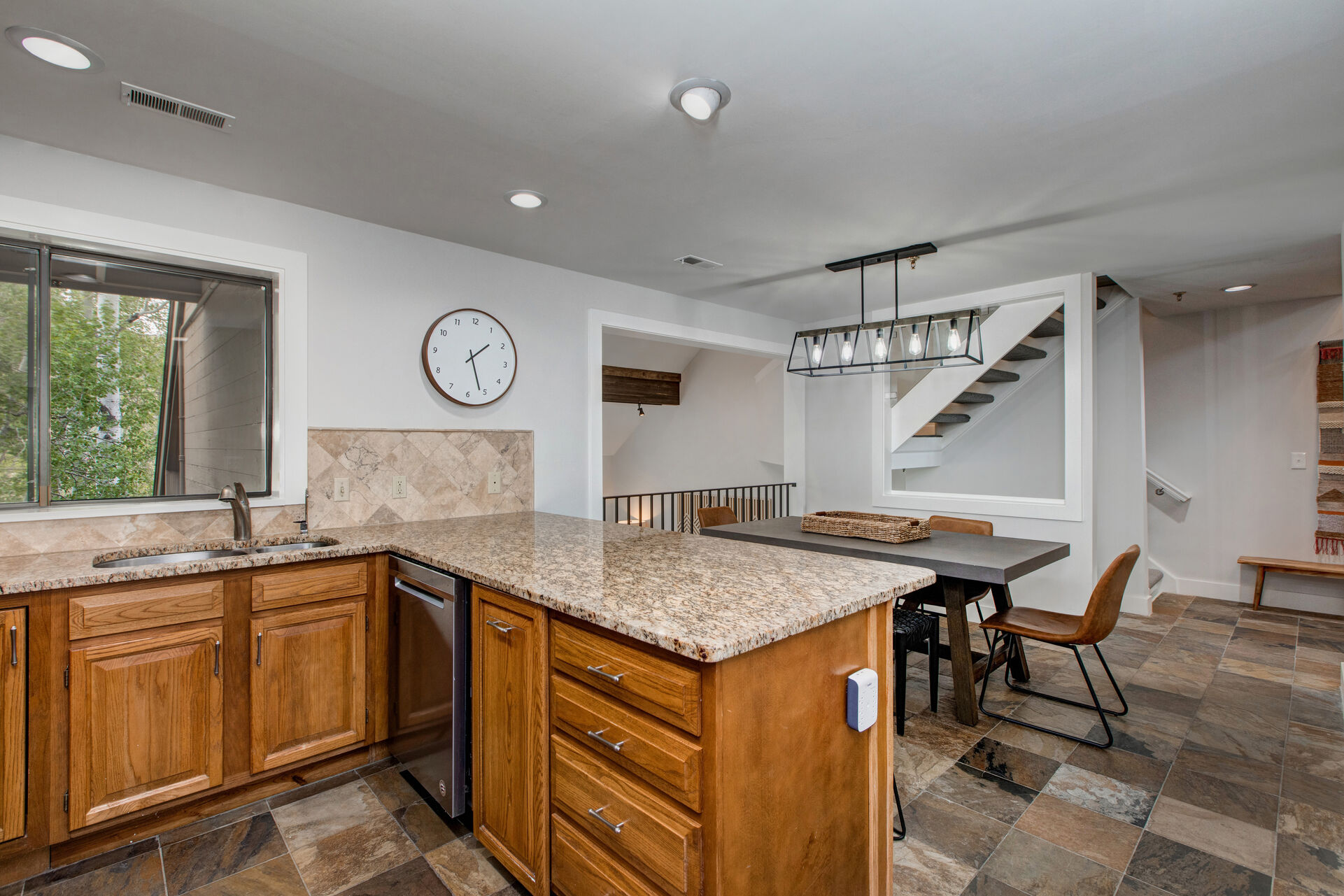 Kitchen with stone countertops, stainless steel appliances, bar seating for four, and garage and laundry room access
