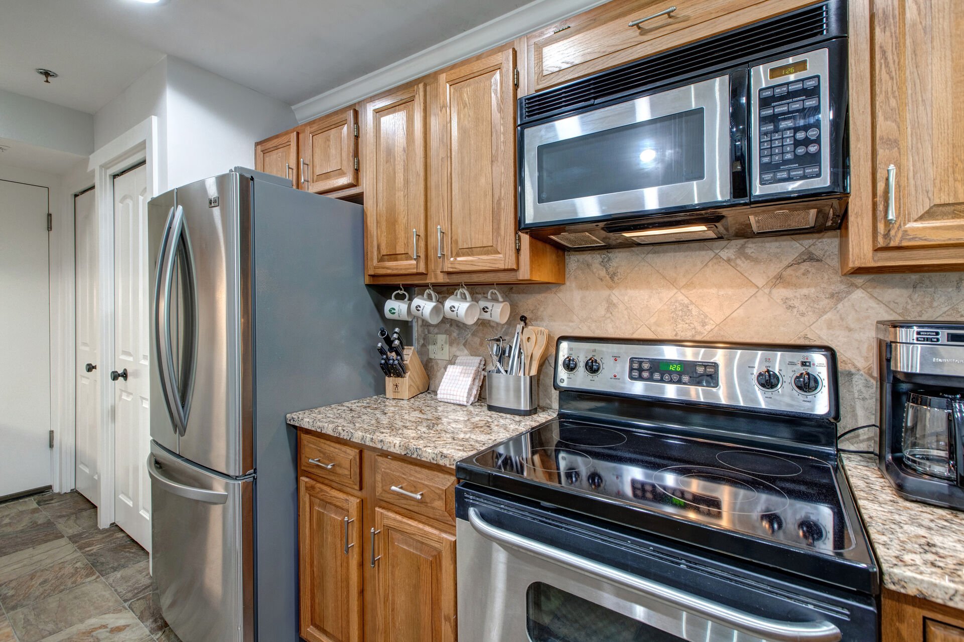 Kitchen with stone countertops, stainless steel appliances, bar seating for four, and garage and laundry room access