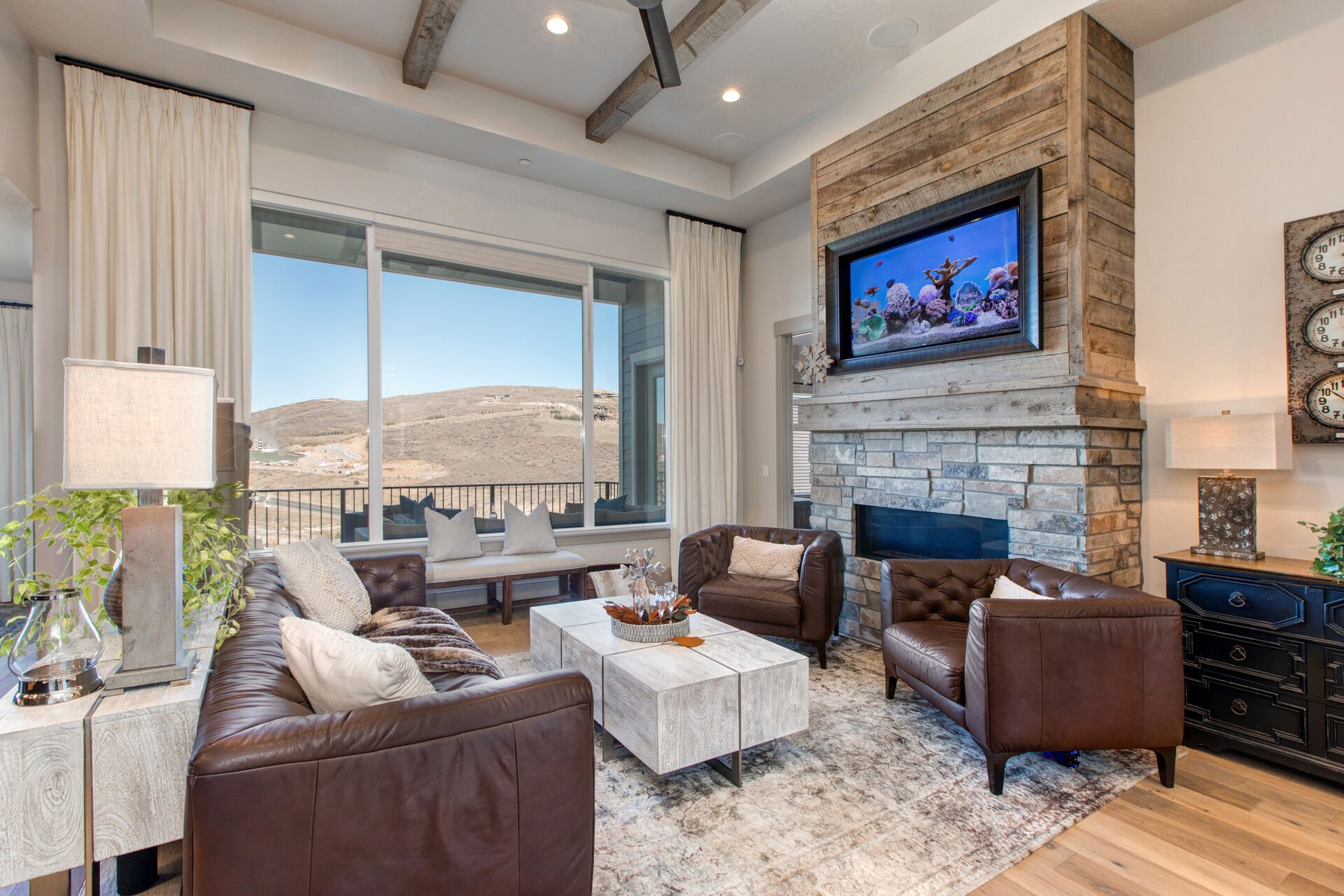 Upper level living room with leather furnishings, smart TV, gas fireplace, reading bench, and views of the surrounding area and mountains