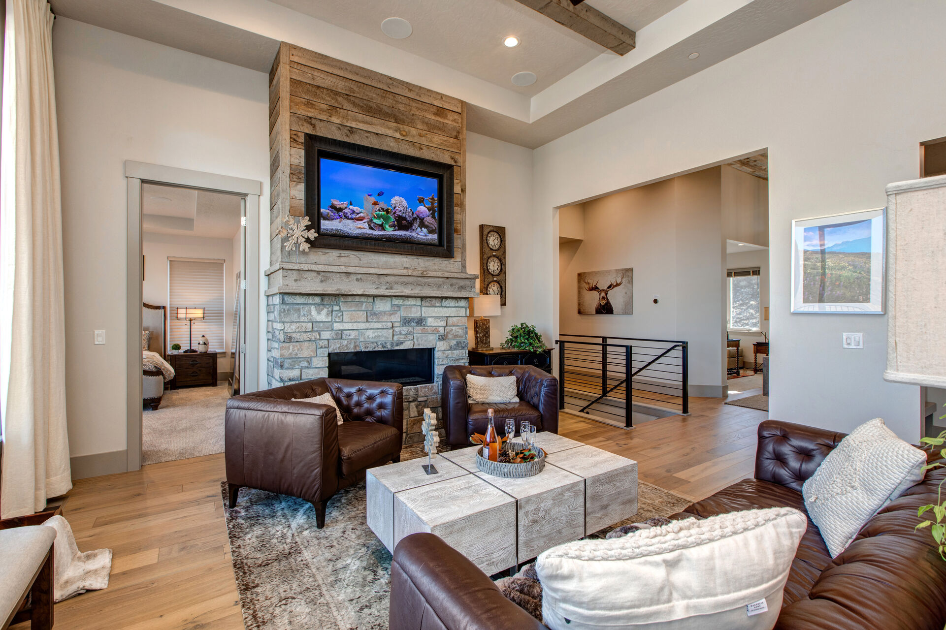 Upper level living room with leather furnishings, smart TV, gas fireplace, reading bench, and views of the surrounding area and mountains