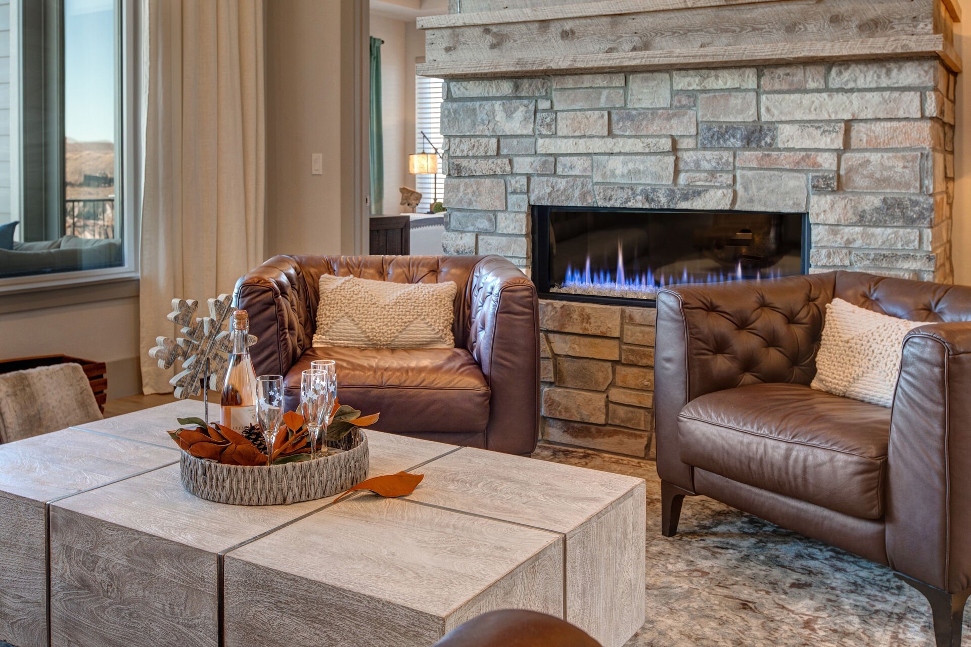 Upper level living room with leather furnishings, smart TV, gas fireplace, reading bench, and views of the surrounding area and mountains