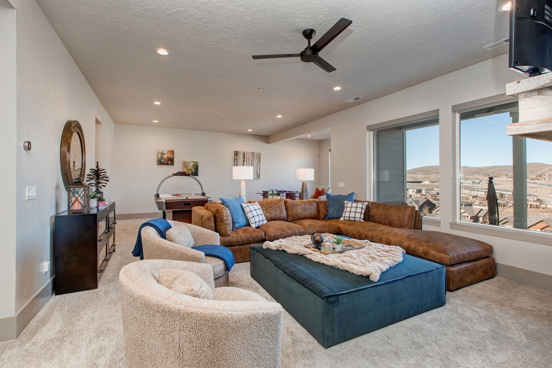 Lower Level Living and Game Room with over-sized leather sectional, plush arm chairs & ottoman, gas fireplace, Samsung smart tv, half bathroom, foosball table, air hockey table, and private patio hot tub access