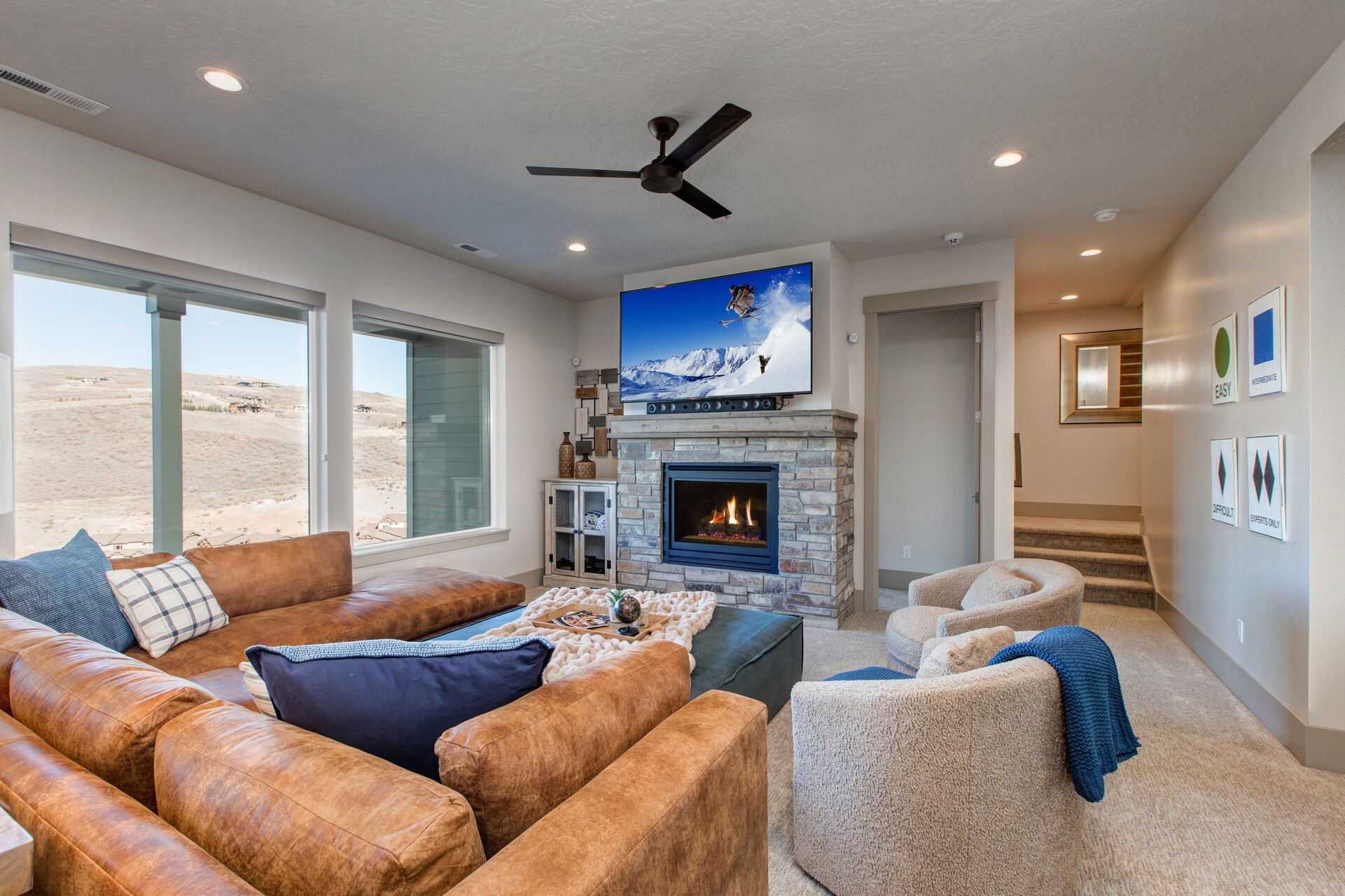 Lower Level Living and Game Room with over-sized leather sectional, plush arm chairs & ottoman, gas fireplace, Samsung smart tv, half bathroom, foosball table, air hockey table, and private patio hot tub access