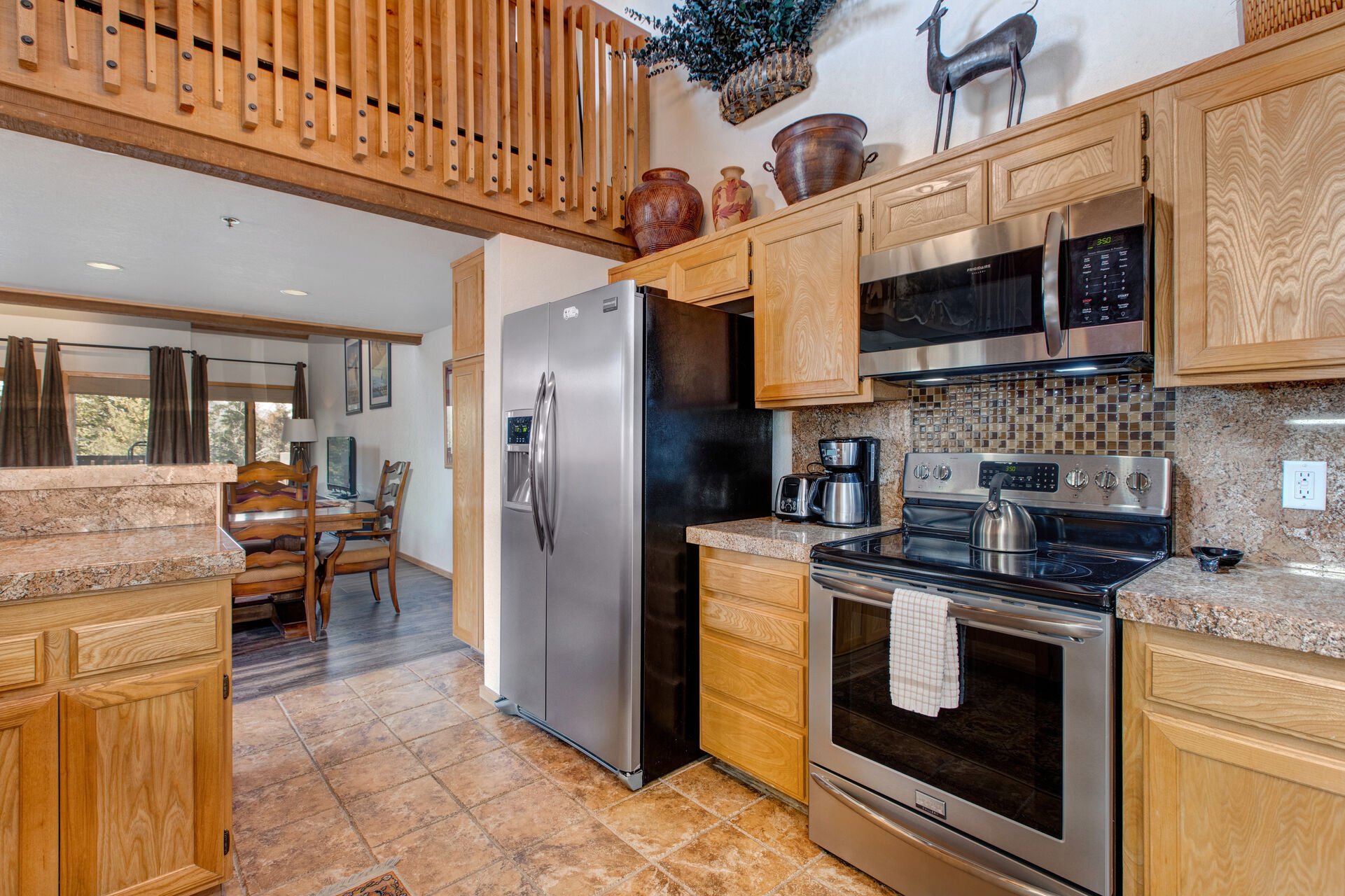 Fully Equipped Kitchen with stainless steel Frigidaire appliances, stone countertops, breakfast nook with seating for four, and bar seating for four