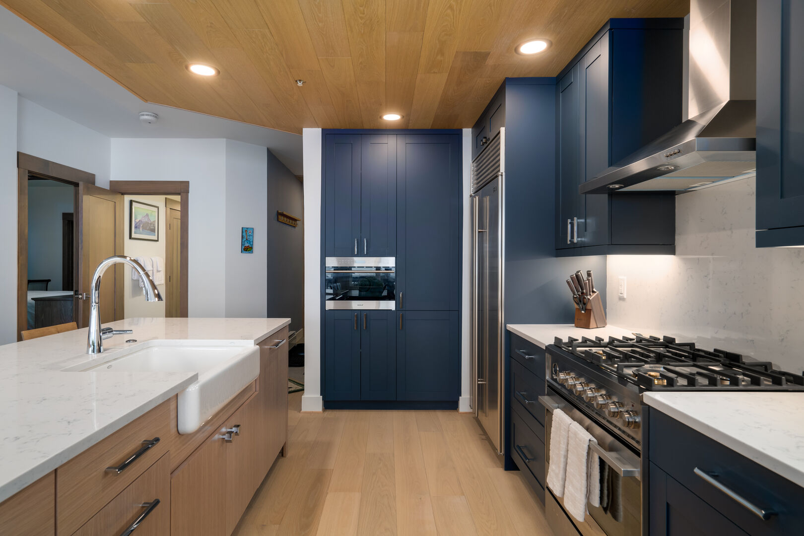 Custom blue cabinetry pops in our kitchen, below the new wood paneled ceiling.
