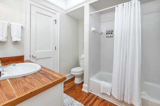 Bathroom features a tub/shower combo and wooden countertops