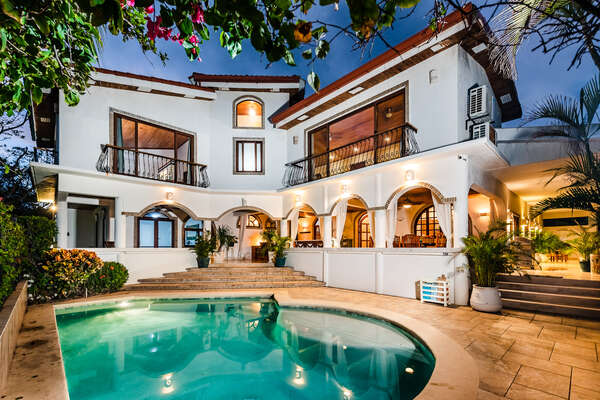 Front facade at night: A starlit paradise with a sparkling pool.