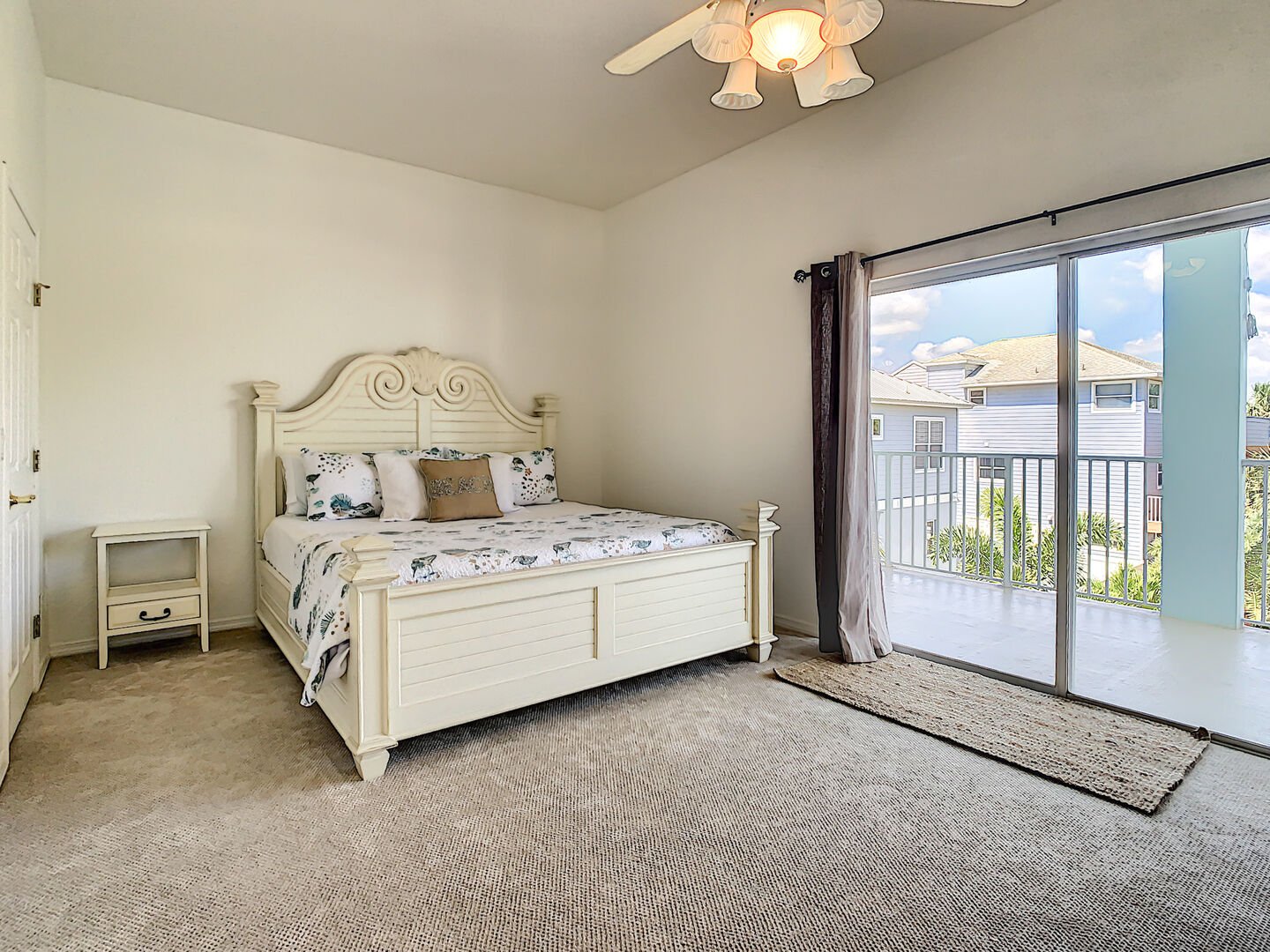 Master bedroom with king size bed and sliders to the balcony overlooking pool area.