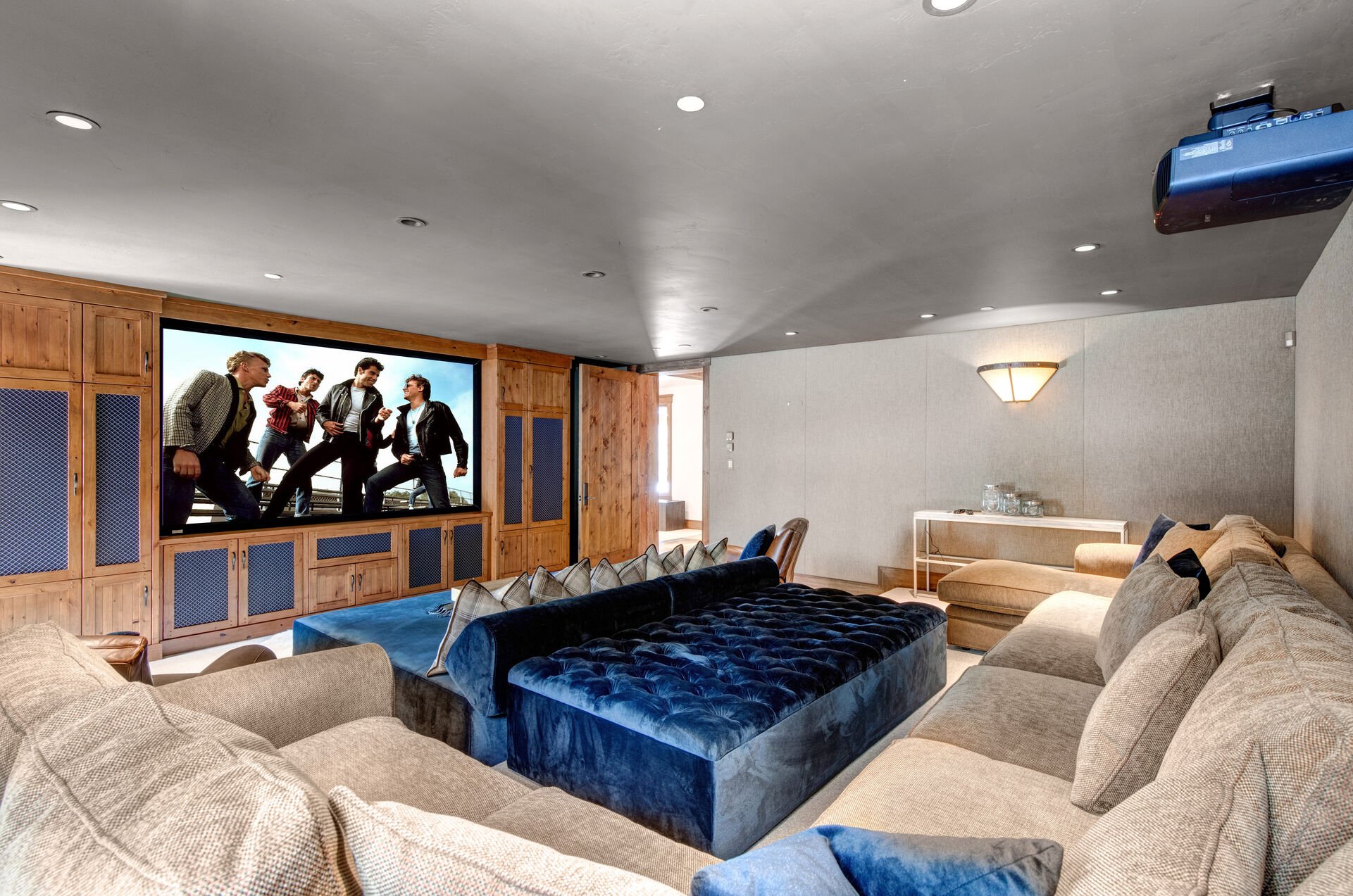 Ground level theater room with large projector, soundproof walls, oversized sectional and sound system