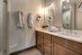 Upper Level Shared Bathroom with dual vanities and large tiled shower