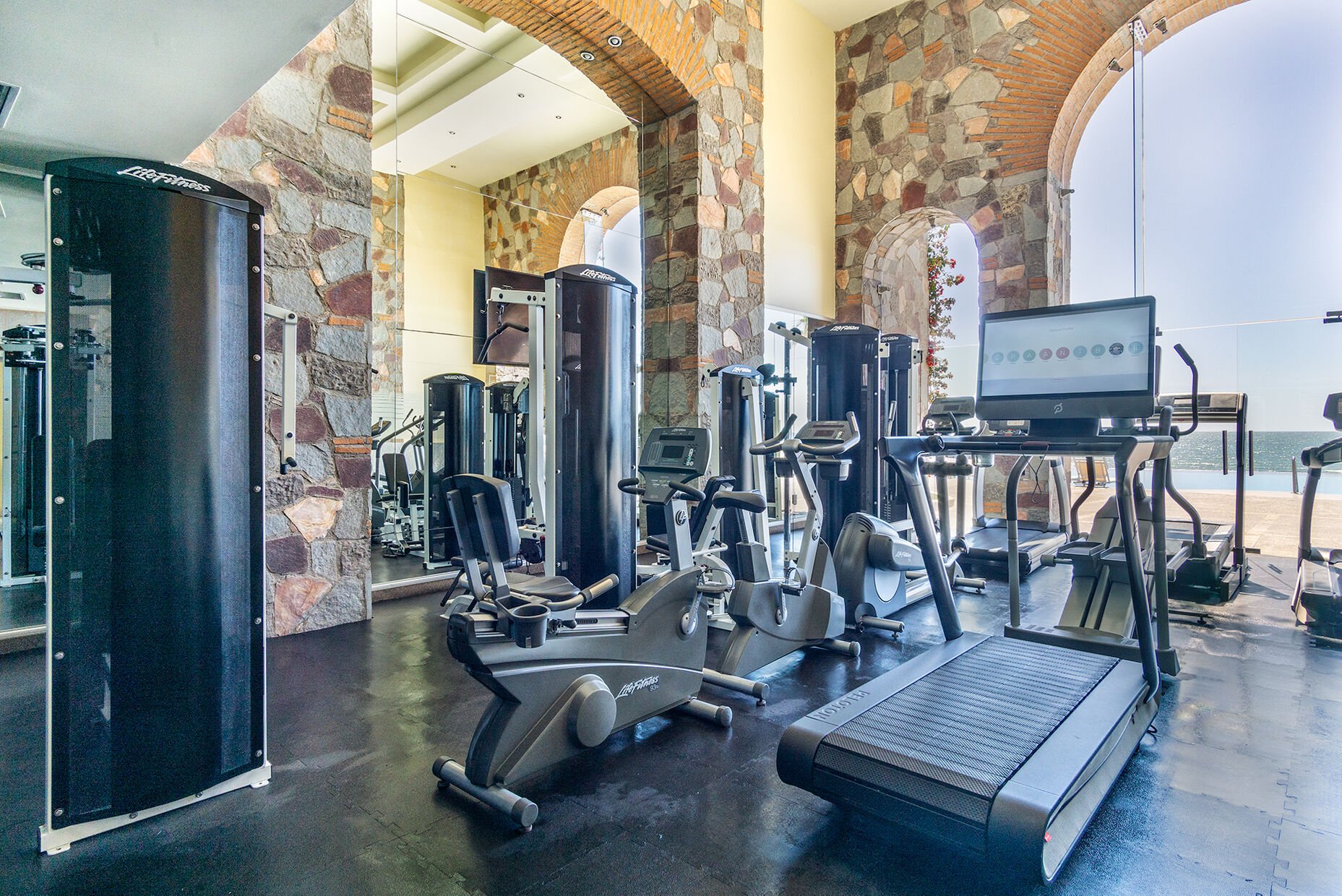 The gym has tall arch d windows that bring the ocean inside as you workout!