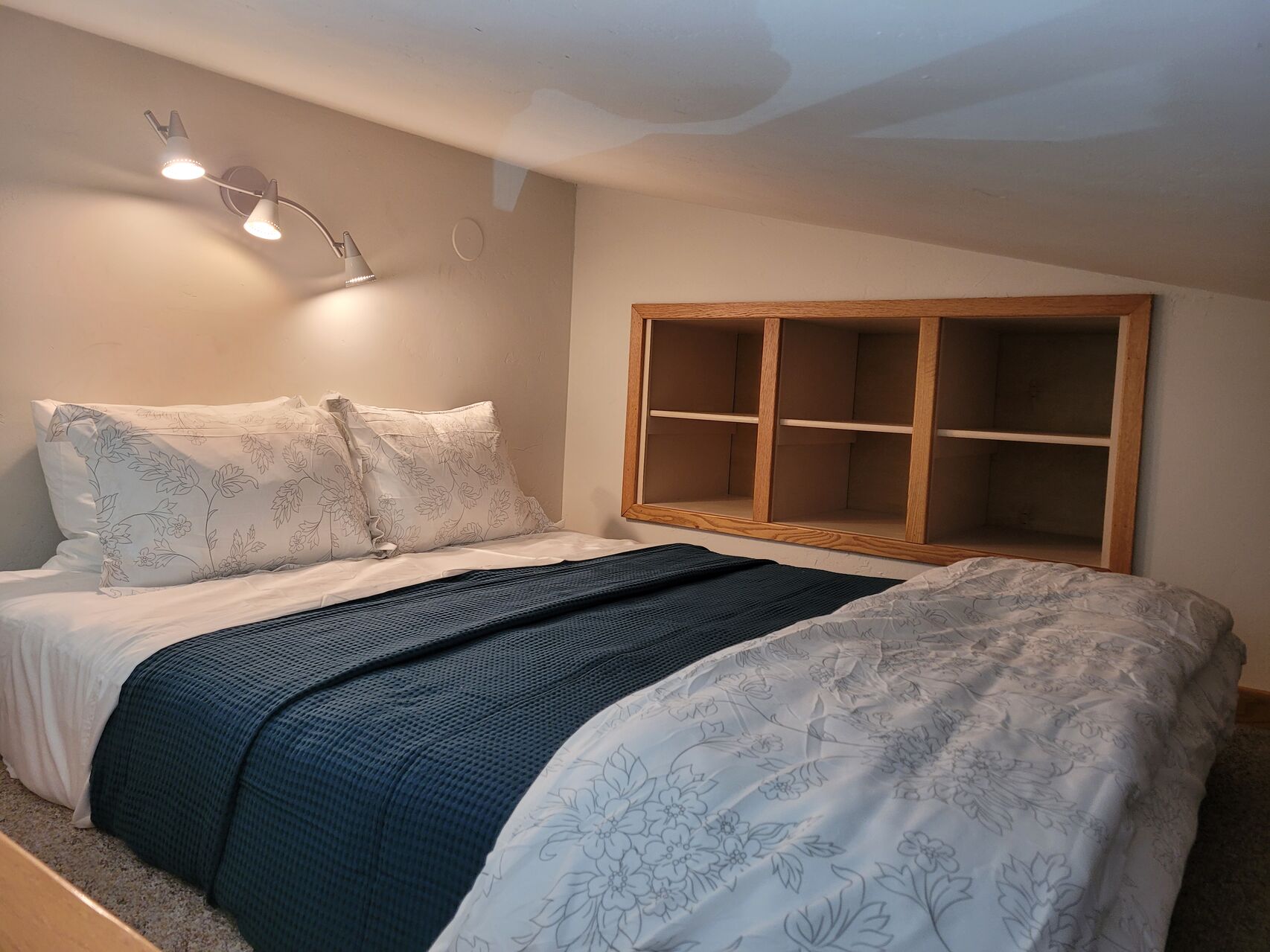 Large bed with blue and white covers and built-in shelves
