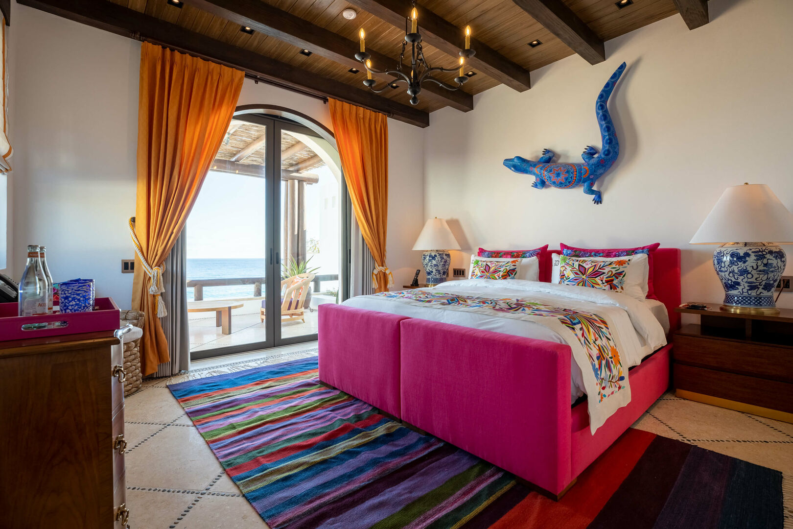 A large lizard decoration hangs above a red bed in one of the bedrooms of La Datcha.