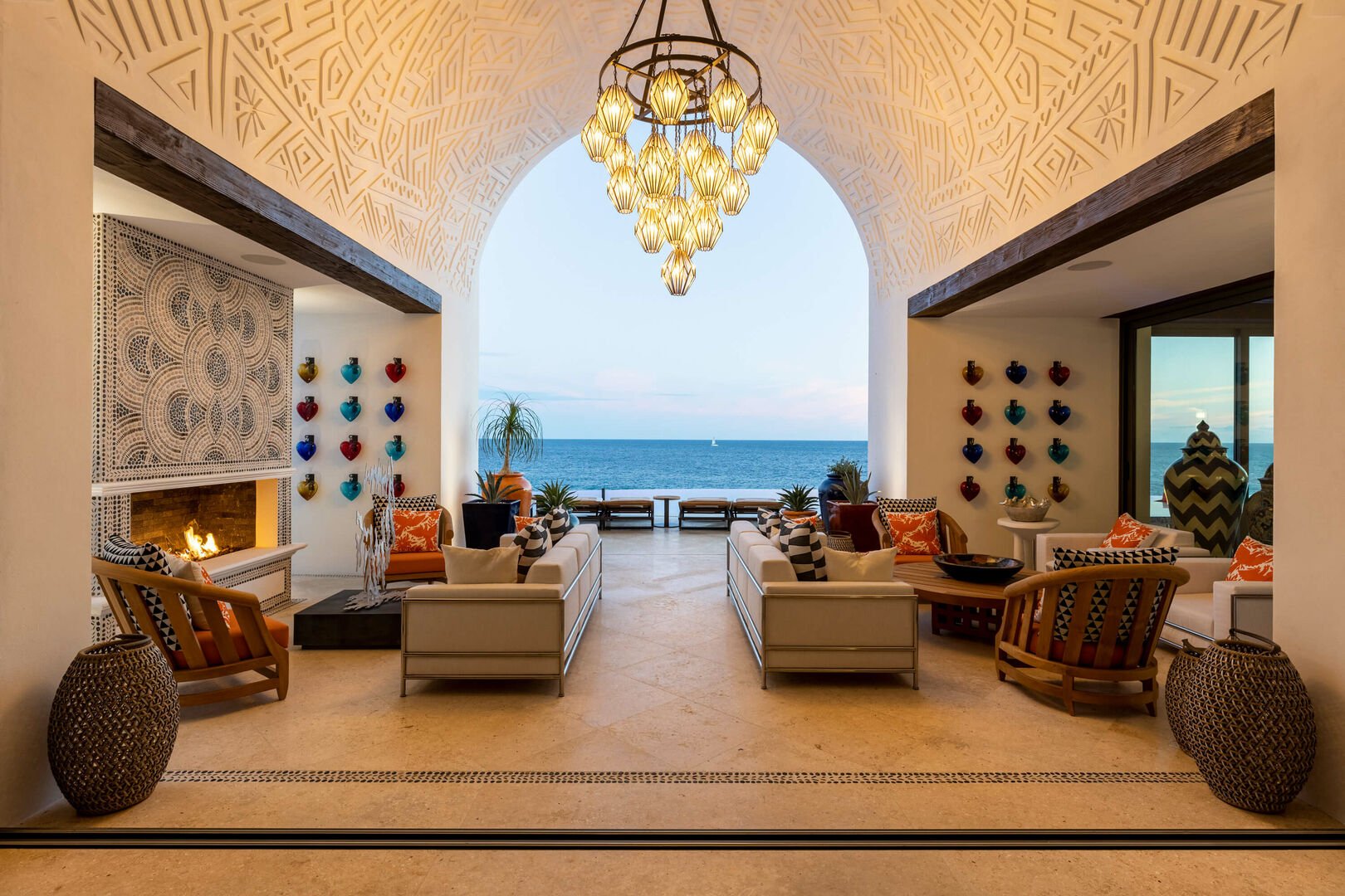 A sitting area with multiple chairs and couches, and a large archway facing the ocean.