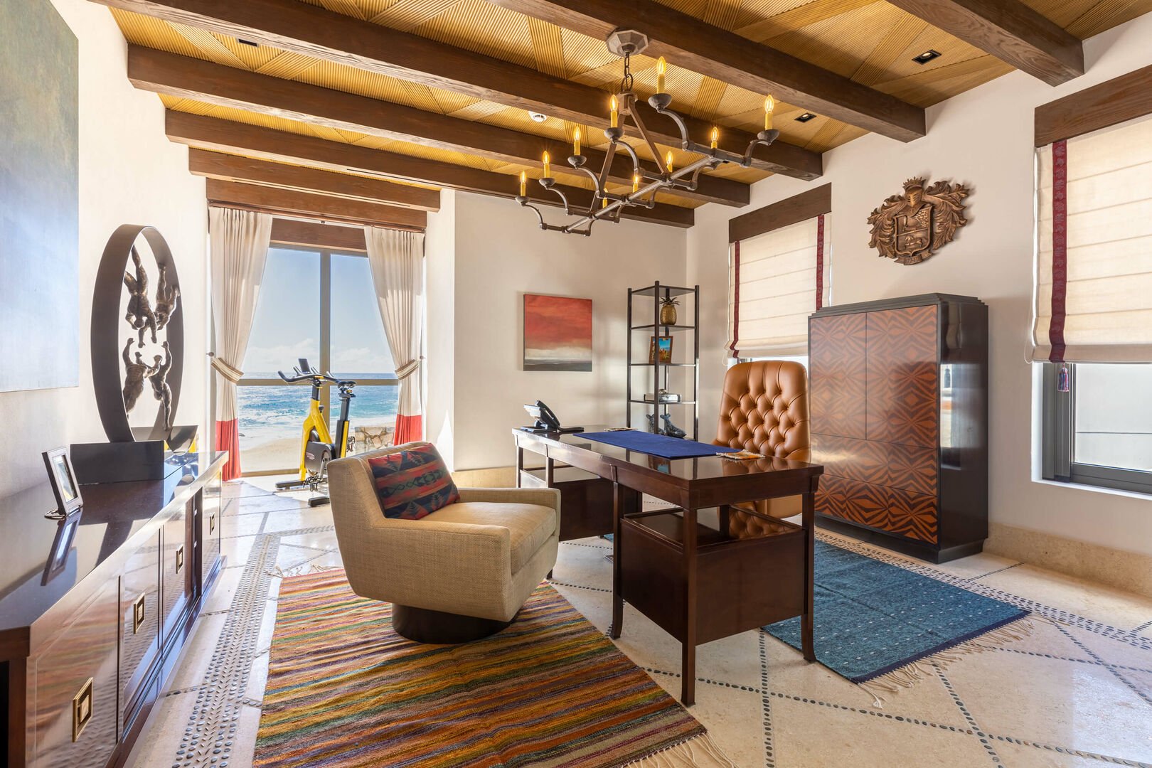 An office in this Los Cabos beachfront villa, complete with a desk, comfortable chairs, and an elliptical.