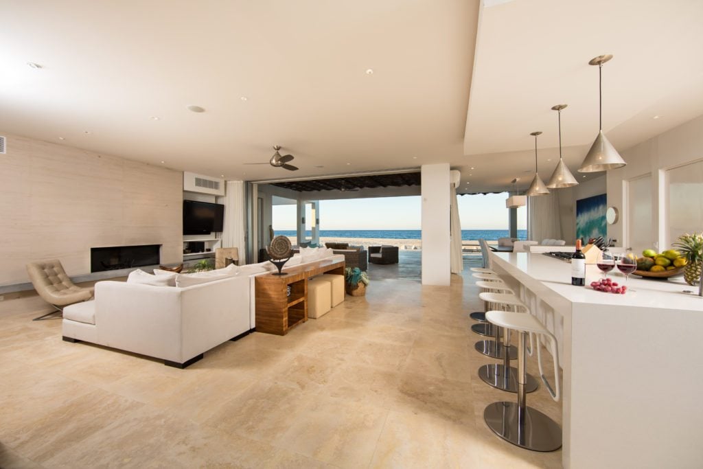 The living room and bar seating by the kitchen, by a large door leading to the beach.