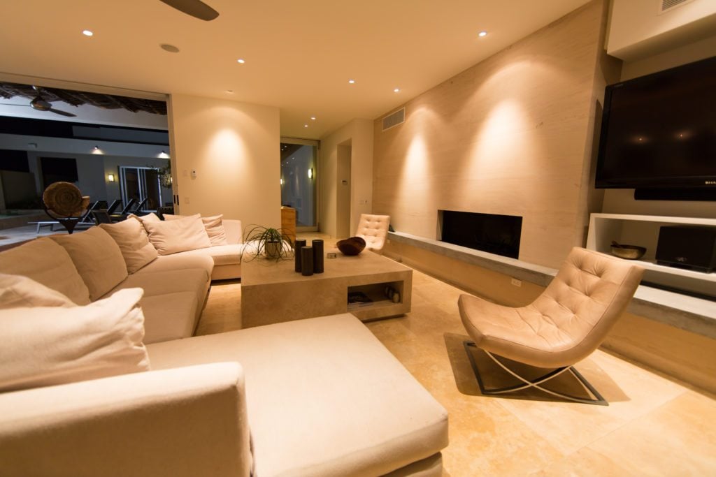 A large sectional couch wraps around a coffee table in front of the wall-mounted TV and fireplace of the living area.