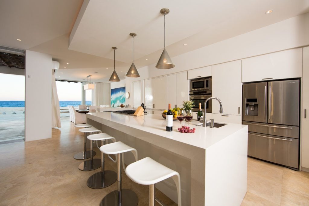 The kitchen of La Ribera house, with a large island and bar seating in front of stainless steel appliances.