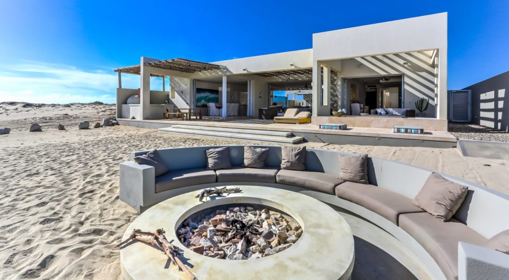 The rear exterior of La Ribera house features a fire pit surrounded by a semi-circle couch.