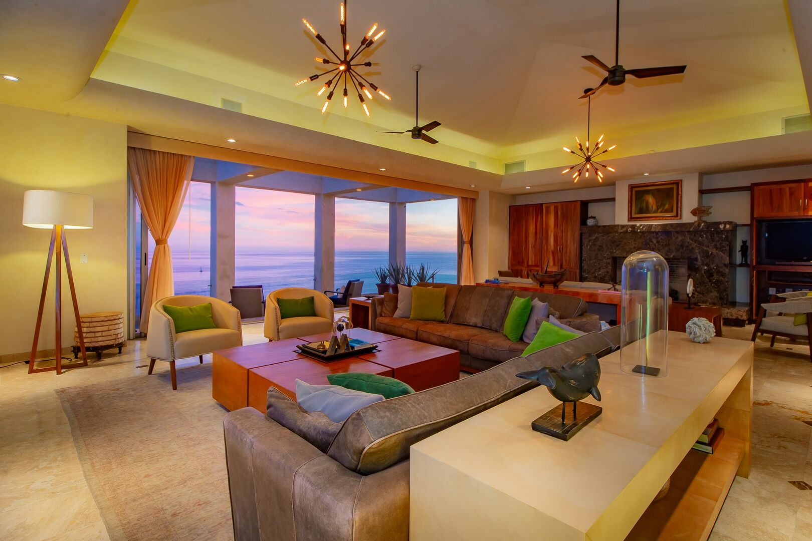 A large living room with a big sectional couch and a view of the ocean through the windows.