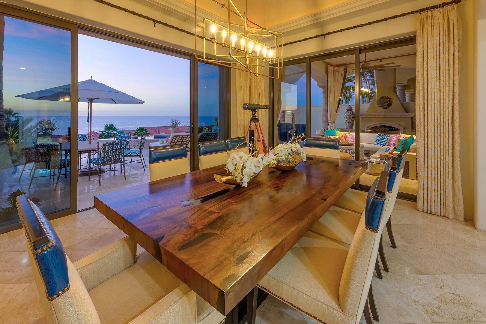 A dining table with 8 chairs near an open sliding door leading to the pool patio.